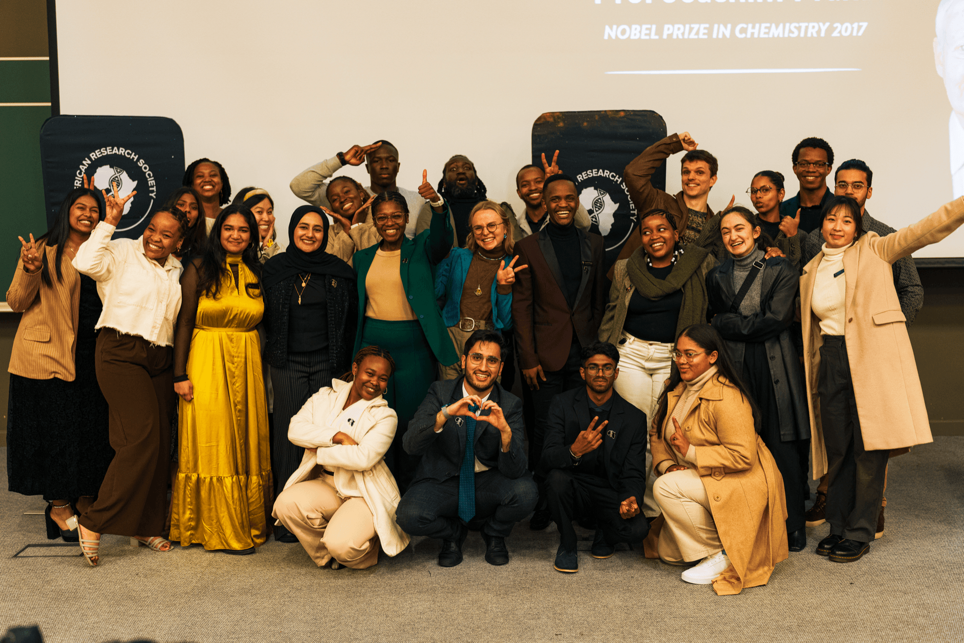 The African Research Society team celebrating together at an event, with a Nobel Prize slide behind them
